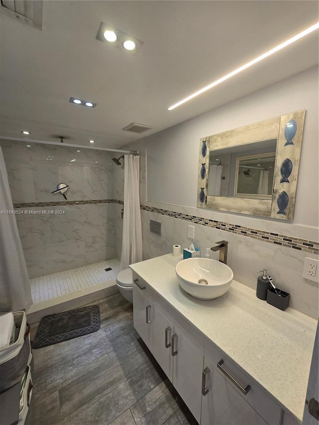 bathroom featuring toilet, wood finished floors, vanity, visible vents, and a shower stall