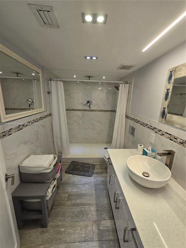 bathroom with a stall shower, visible vents, and tile walls