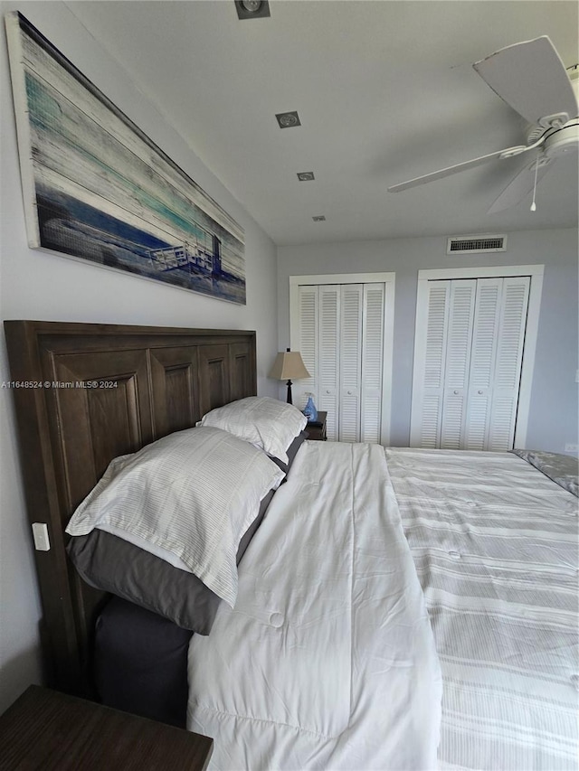 bedroom featuring multiple closets, visible vents, and ceiling fan