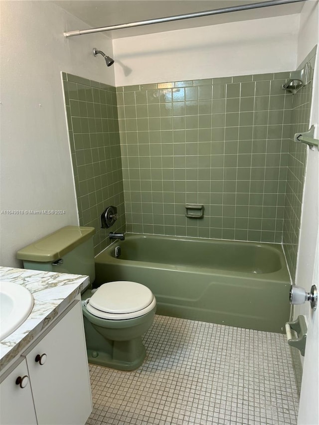 full bathroom featuring tile patterned flooring, tiled shower / bath, vanity, and toilet