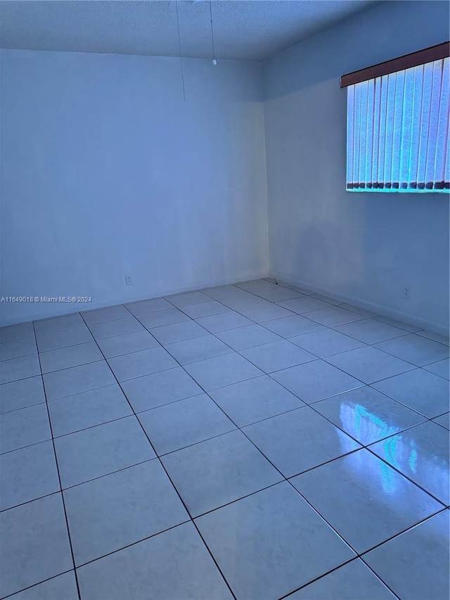 tiled empty room featuring a textured ceiling