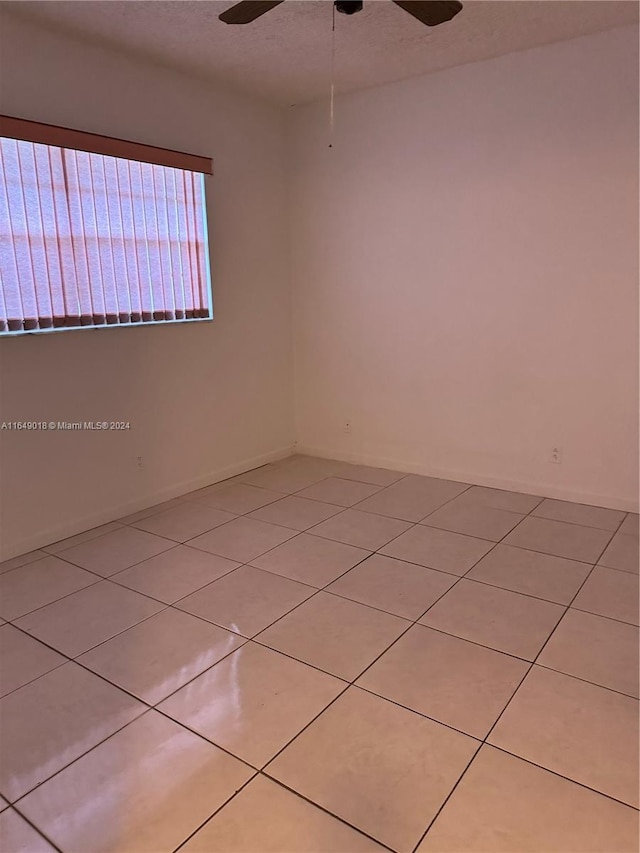 tiled empty room featuring ceiling fan