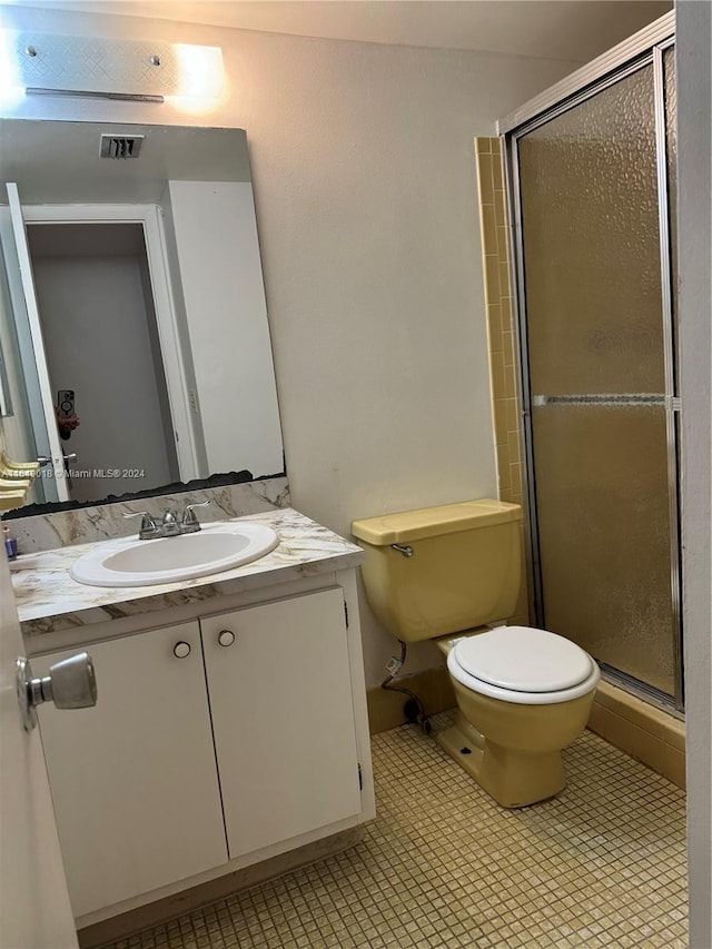 bathroom featuring vanity, a shower with shower door, and toilet