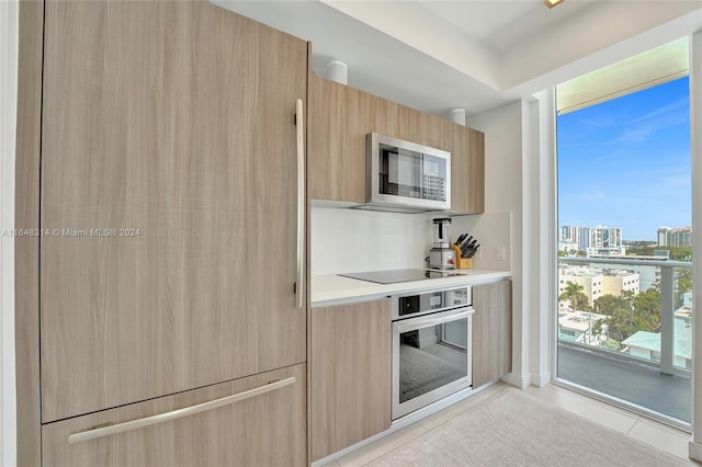 kitchen featuring stainless steel appliances, light tile patterned floors, and light brown cabinetry