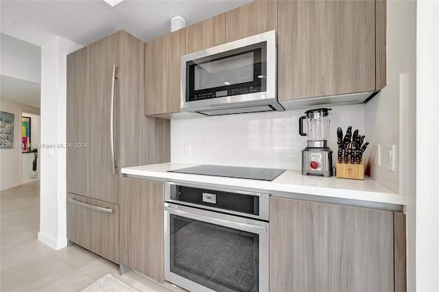 kitchen with light brown cabinetry, light tile patterned floors, and stainless steel appliances