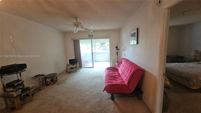 sitting room featuring ceiling fan, a textured ceiling, and light carpet