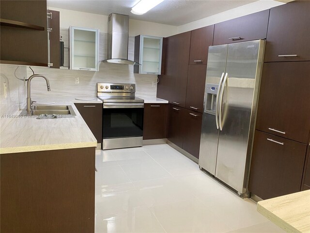 kitchen featuring wall chimney range hood, backsplash, appliances with stainless steel finishes, sink, and light tile patterned flooring