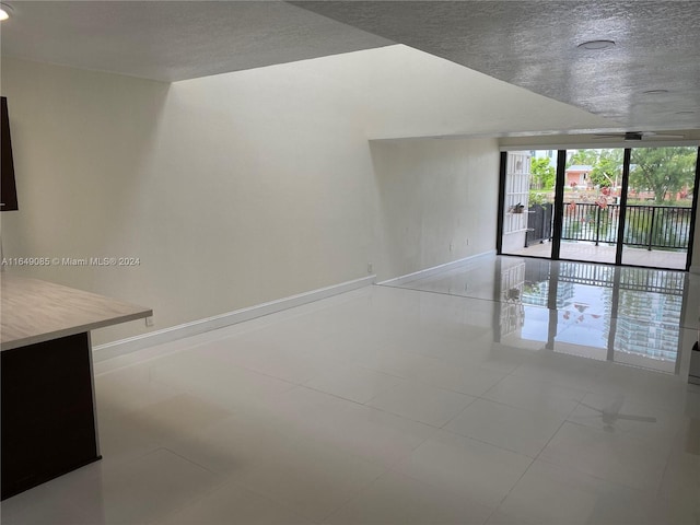 spare room featuring tile patterned floors, a textured ceiling, and a wall of windows