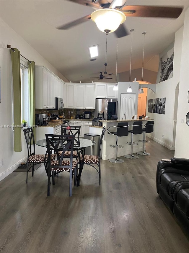 dining space with ceiling fan, high vaulted ceiling, and dark hardwood / wood-style flooring