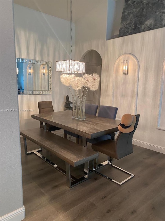 dining space with high vaulted ceiling, an inviting chandelier, and dark hardwood / wood-style floors