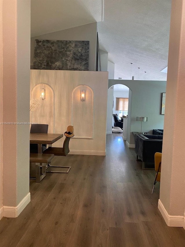 corridor featuring a textured ceiling, lofted ceiling, and dark hardwood / wood-style floors