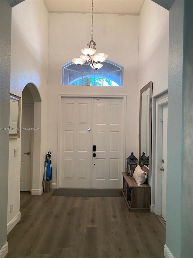 foyer featuring a towering ceiling, a notable chandelier, and dark wood-type flooring