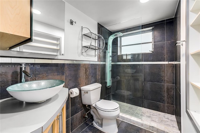 bathroom featuring toilet, tile walls, a tile shower, vanity, and tile patterned flooring