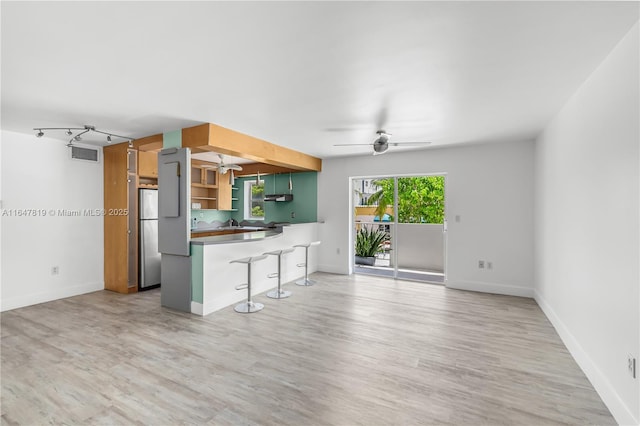 unfurnished living room featuring wood-type flooring, rail lighting, and ceiling fan