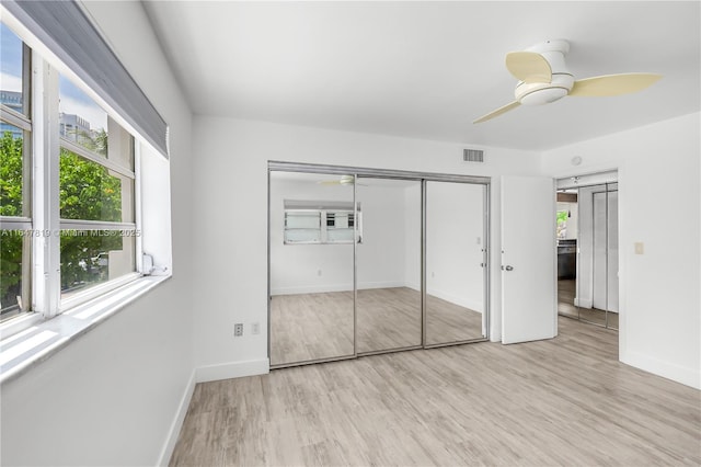 unfurnished bedroom with ceiling fan, a closet, and light wood-type flooring