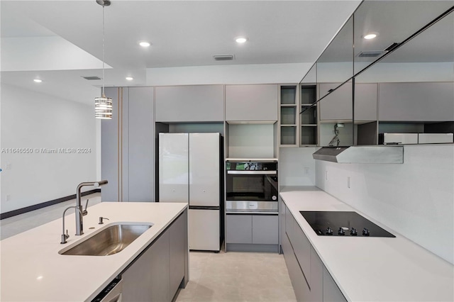 kitchen featuring white refrigerator, gray cabinetry, stainless steel oven, and sink