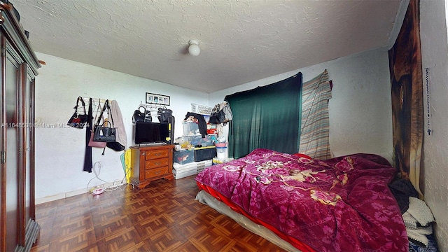 bedroom with a textured ceiling and dark parquet floors