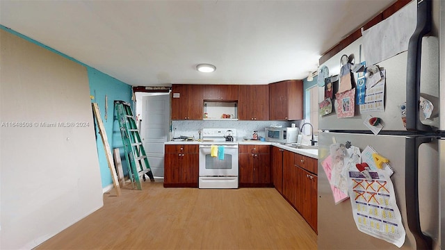 kitchen with decorative backsplash, appliances with stainless steel finishes, light wood-type flooring, and sink