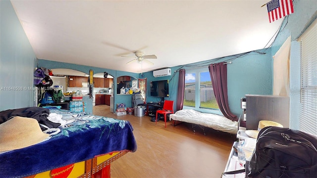 bedroom with an AC wall unit, ceiling fan, and hardwood / wood-style flooring