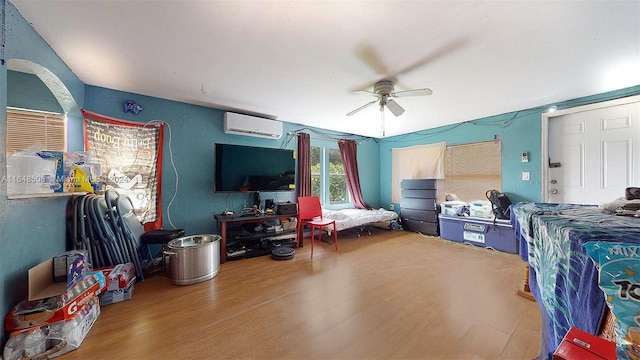 bedroom featuring hardwood / wood-style floors, ceiling fan, and a wall mounted air conditioner