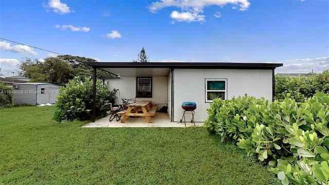 rear view of property featuring a yard, a patio, and a shed