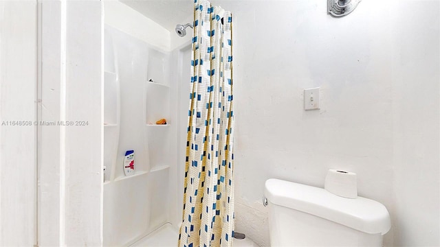 bathroom featuring toilet and curtained shower