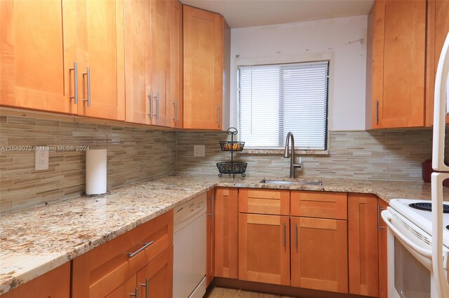 kitchen with light stone countertops, sink, decorative backsplash, and white appliances