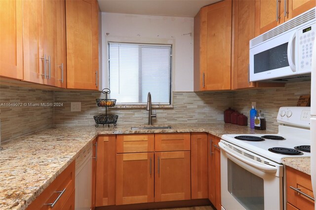 kitchen with sink, decorative backsplash, light stone countertops, and white appliances