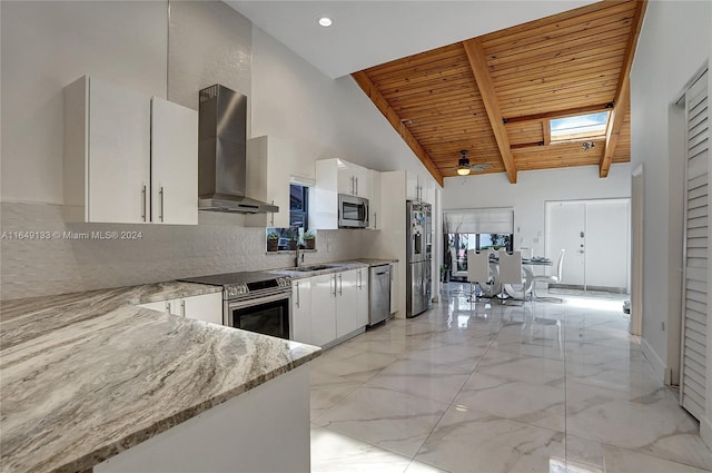 kitchen featuring wood ceiling, light stone counters, stainless steel appliances, wall chimney range hood, and white cabinetry