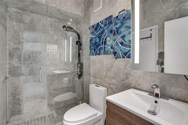 full bath with toilet, visible vents, vanity, tile walls, and a stall shower