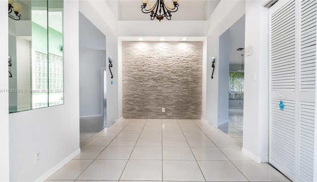 corridor featuring an inviting chandelier, light tile patterned floors, and a towering ceiling