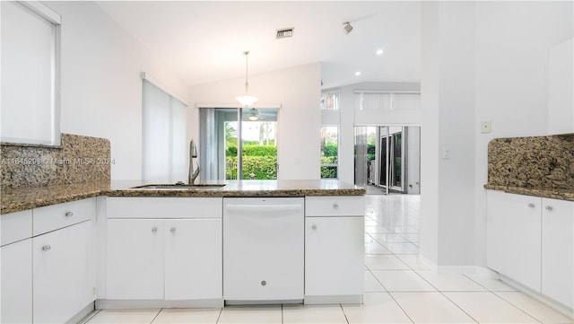 kitchen with dark stone countertops, a sink, a peninsula, and dishwasher