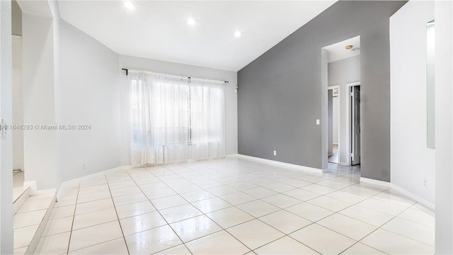 tiled spare room featuring lofted ceiling