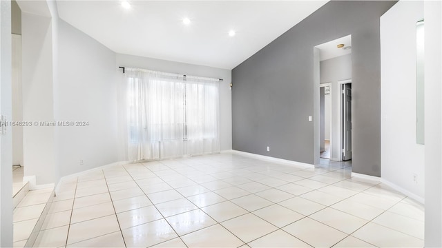 spare room with lofted ceiling, recessed lighting, baseboards, and light tile patterned floors