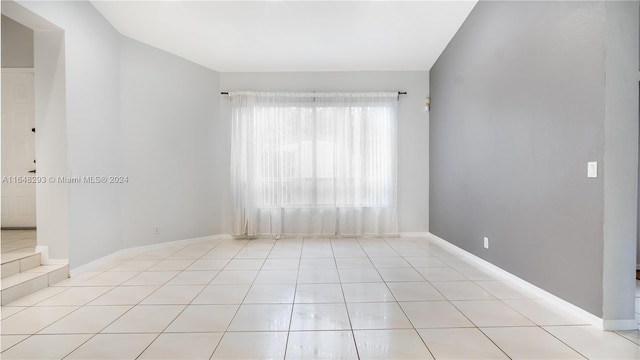 tiled spare room featuring baseboards