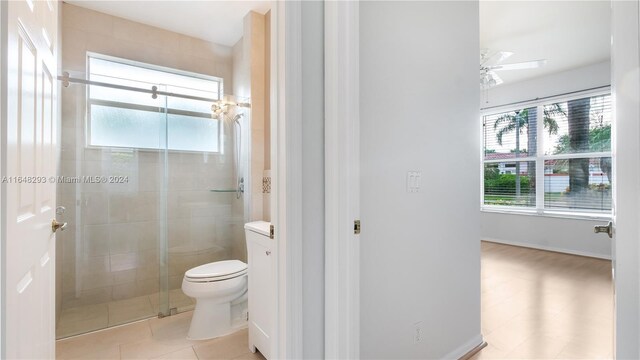 bathroom with toilet, an enclosed shower, ceiling fan, and tile patterned flooring