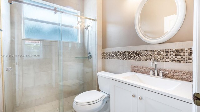 bathroom featuring toilet, walk in shower, vanity, decorative backsplash, and tile walls