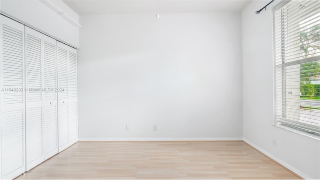 unfurnished bedroom with light wood-style floors, multiple windows, and baseboards