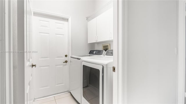 clothes washing area with cabinets, independent washer and dryer, and light tile patterned floors