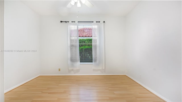 empty room with ceiling fan, wood finished floors, and baseboards