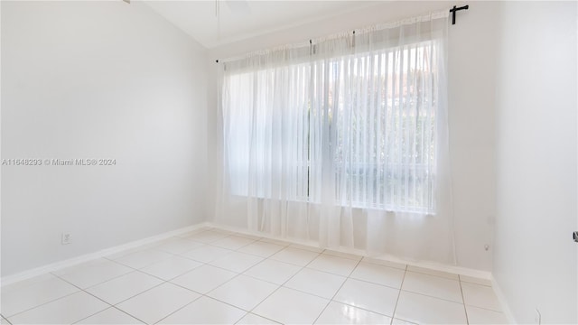 spare room with lofted ceiling, baseboards, and tile patterned floors