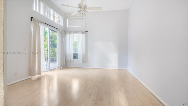 unfurnished room featuring a high ceiling, ceiling fan, and light hardwood / wood-style floors