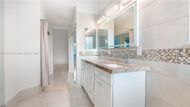 bathroom with tile walls, hardwood / wood-style flooring, decorative backsplash, and vanity