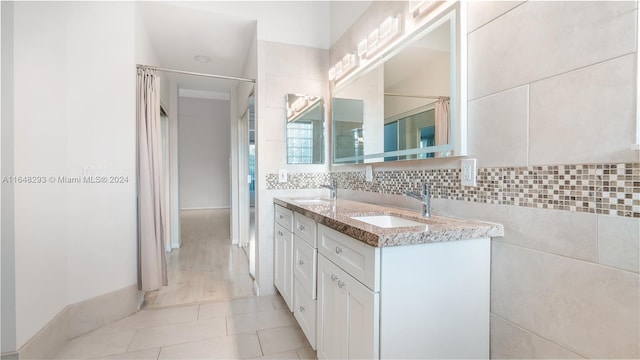 full bath with double vanity, backsplash, a sink, and tile patterned floors