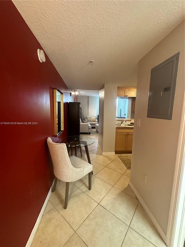 hall featuring sink, a textured ceiling, electric panel, and light tile patterned floors