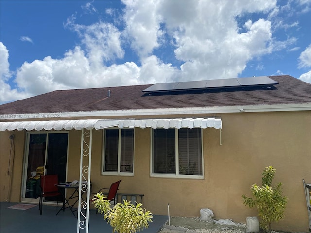 rear view of house with solar panels and a patio area