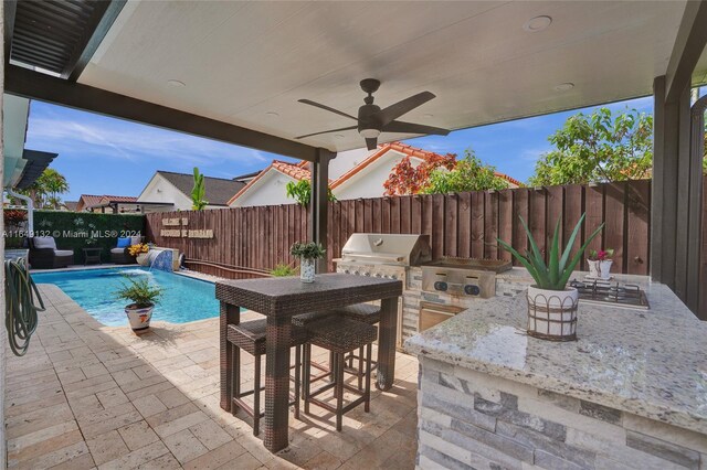 view of patio with ceiling fan, exterior kitchen, a bar, and a fenced in pool