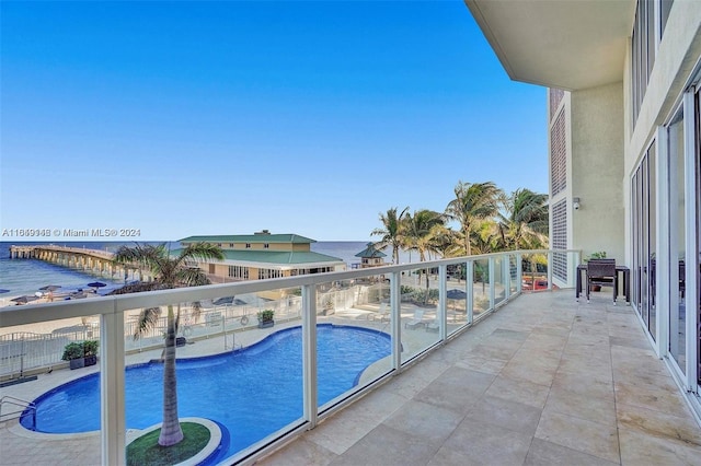 balcony featuring a water view and a fenced in pool