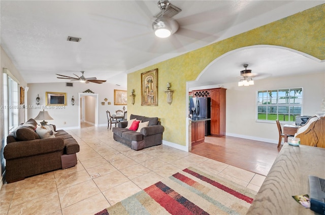 living room featuring arched walkways, light tile patterned flooring, and a ceiling fan