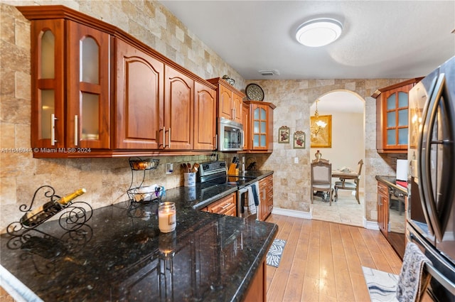 kitchen featuring dark stone counters, stainless steel appliances, and light hardwood / wood-style floors